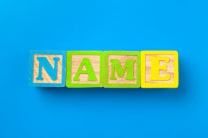 Name. Wooden colorful alphabet blocks on blue background, flat lay, top view